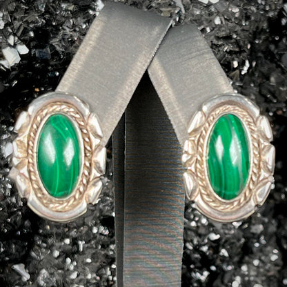 A pair of Southwest style post earrings set with oval cabochon cut malachite stones.