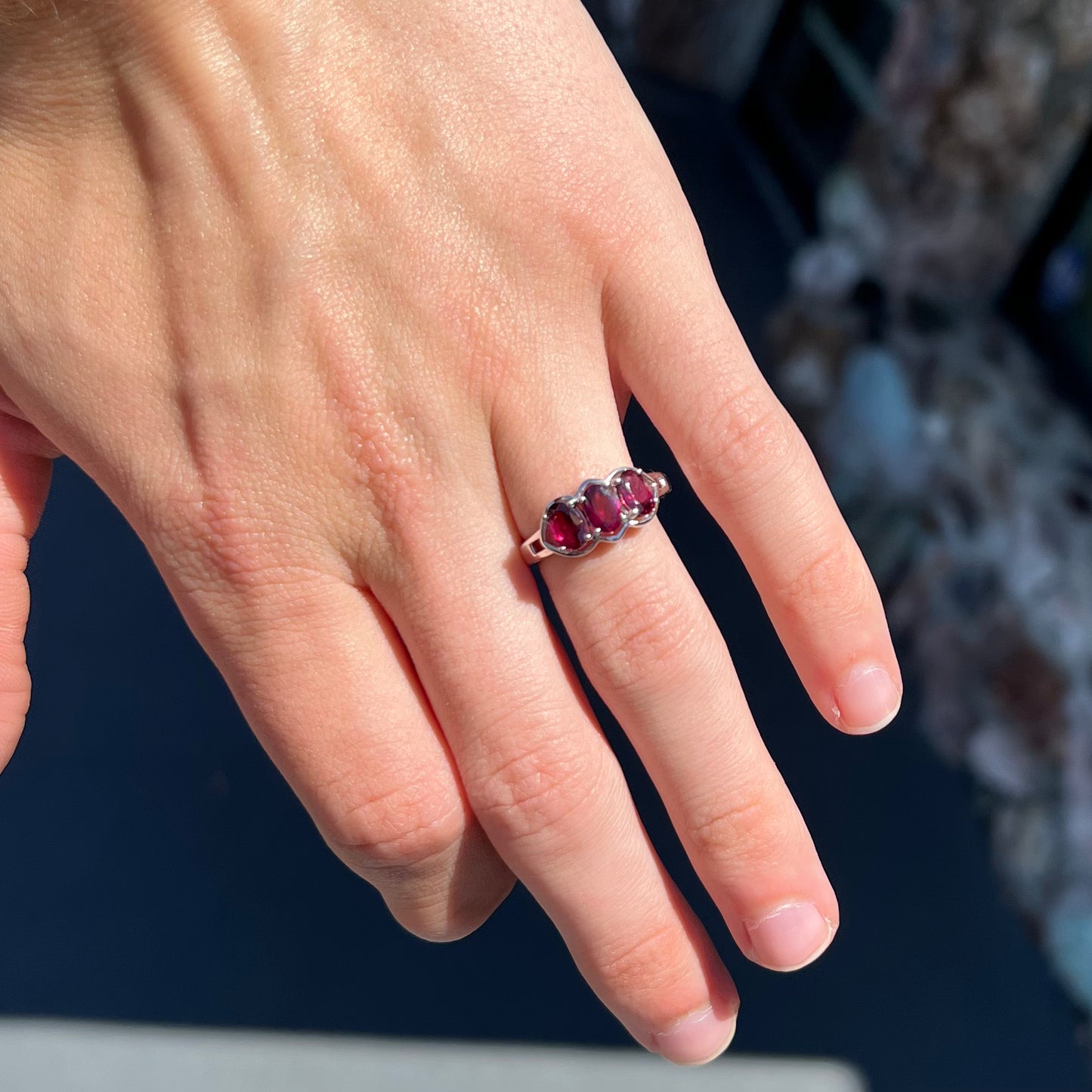 A three stone past, present, and future purple faceted oval cut rhodolite garnet ring.