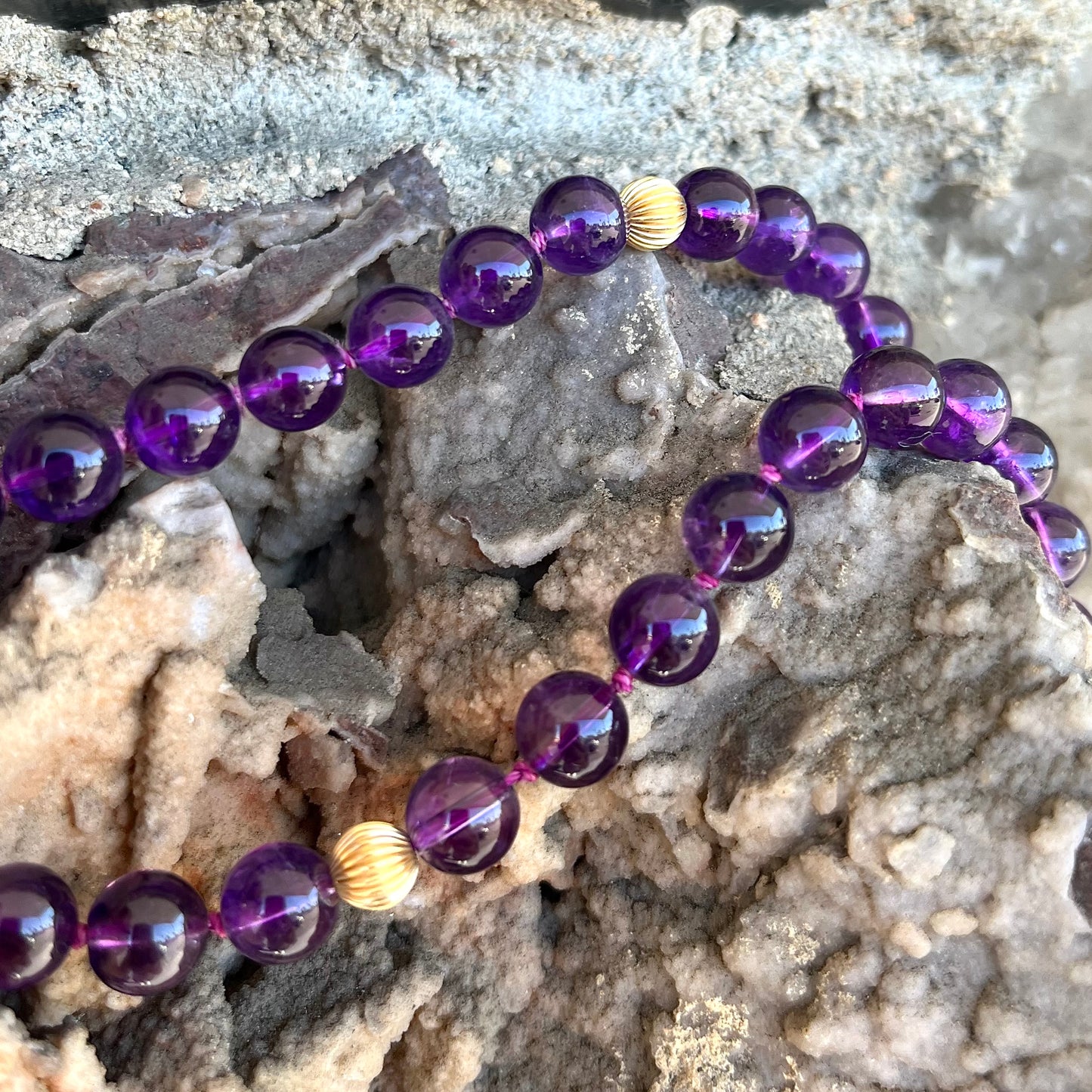 A beaded necklace made with round amethyst and 14k yellow gold beads.