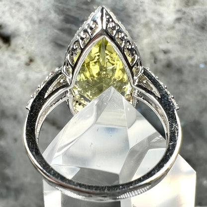 A pear shape lemon quartz set in a sterling silver and white topaz halo ring.