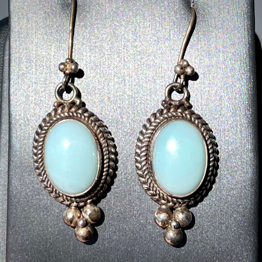 A pair of silver wire dangle earrings set with blue agate stones.  The earrings have a braided rope design.