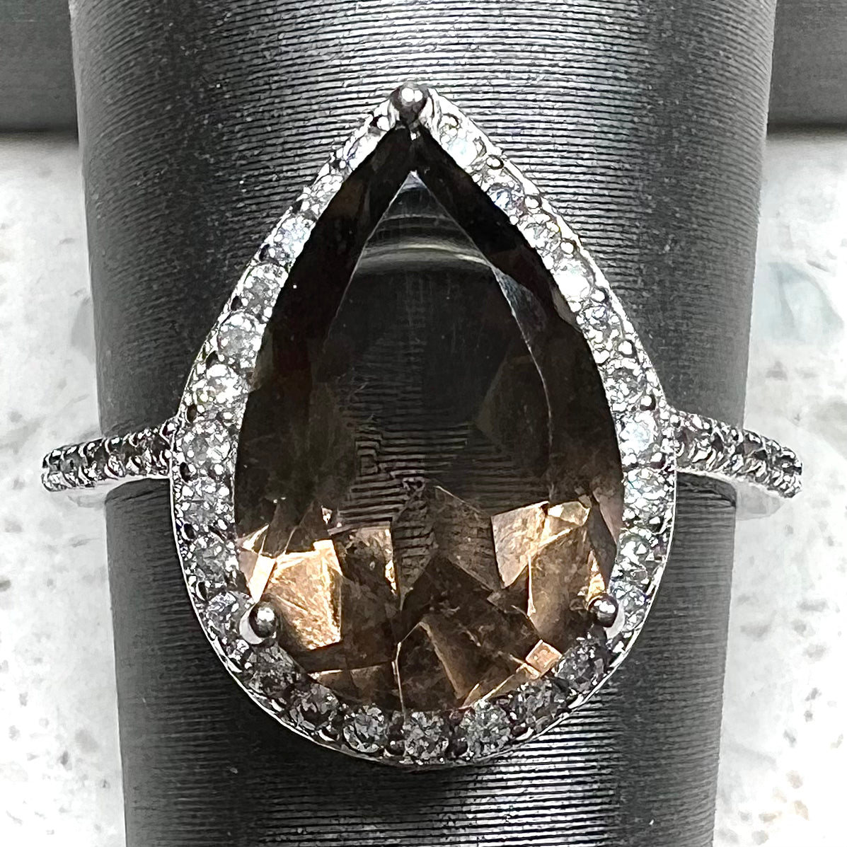 A pear shape smoky quartz set in a sterling silver and CZ halo ring.