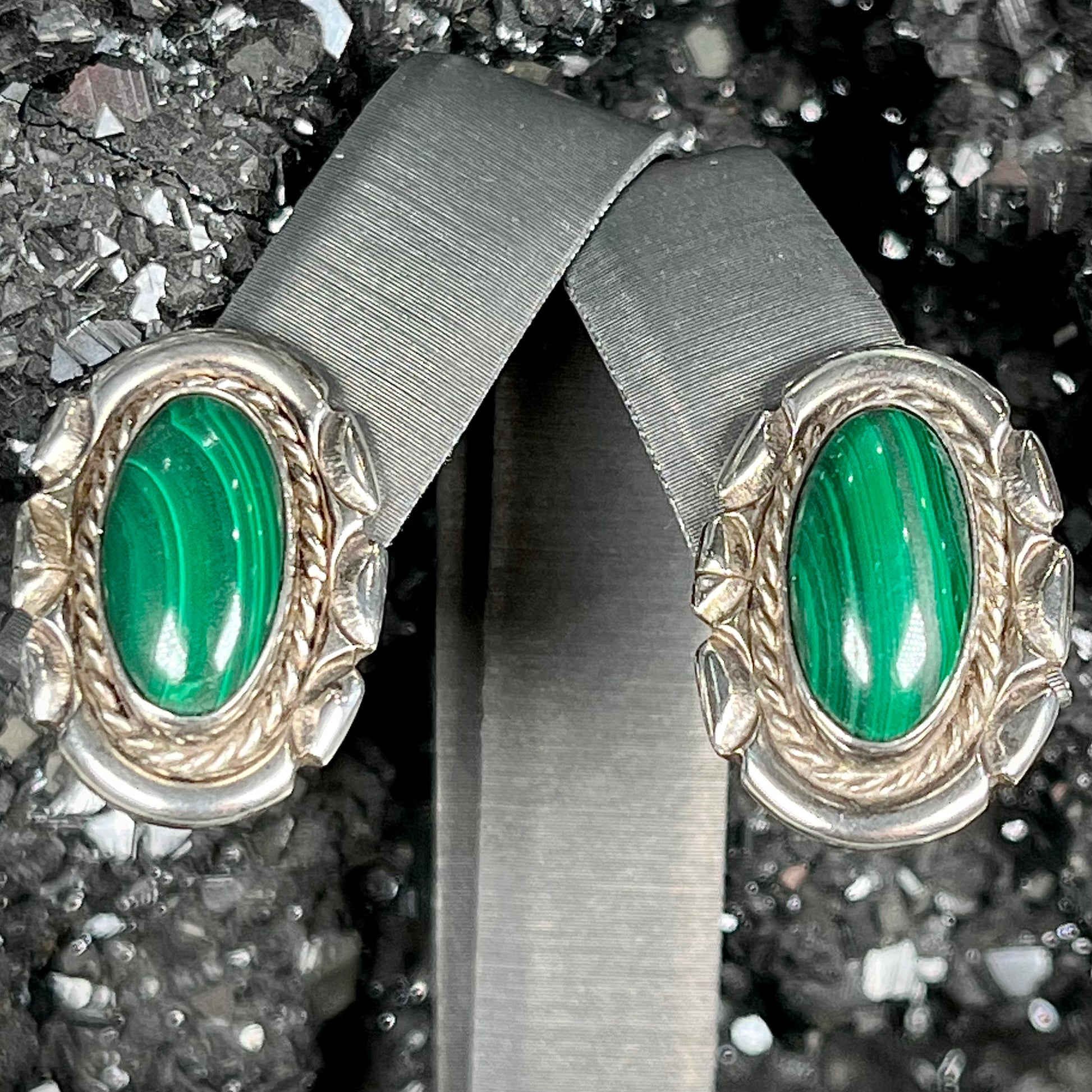 A pair of Southwest style post earrings set with oval cabochon cut malachite stones.