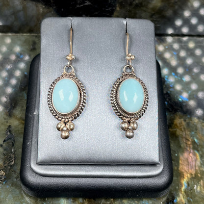 A pair of silver wire dangle earrings set with blue agate stones.  The earrings have a braided rope design.