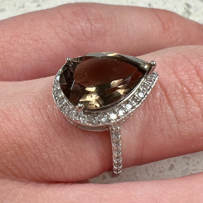 A pear shape smoky quartz set in a sterling silver and CZ halo ring.