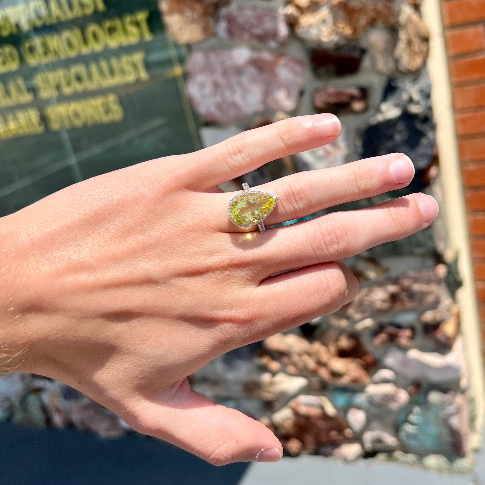 A pear shape lemon quartz set in a sterling silver and white topaz halo ring.