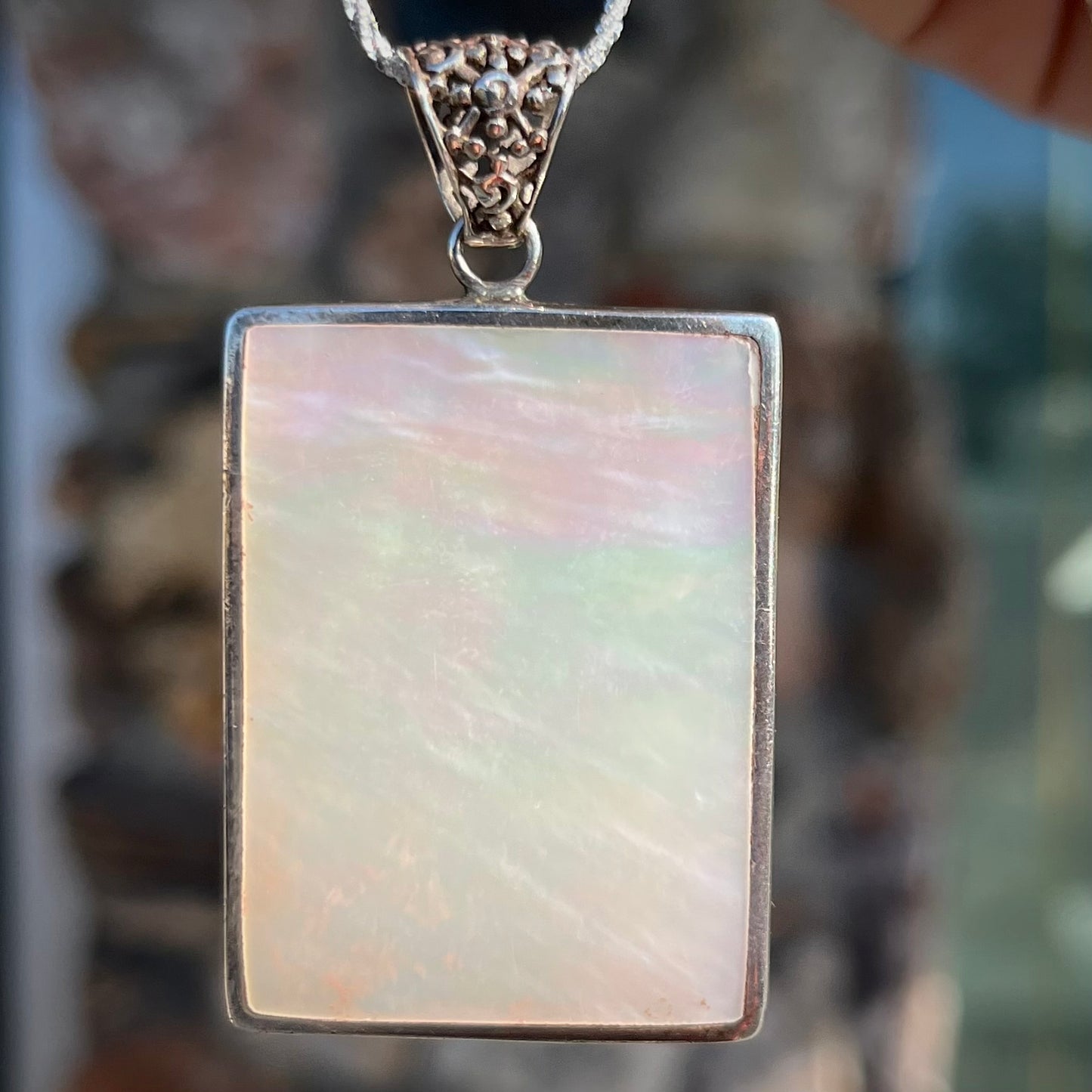 A sterling silver pendant set with rectangular slices of abalone shell and red fossil coral.