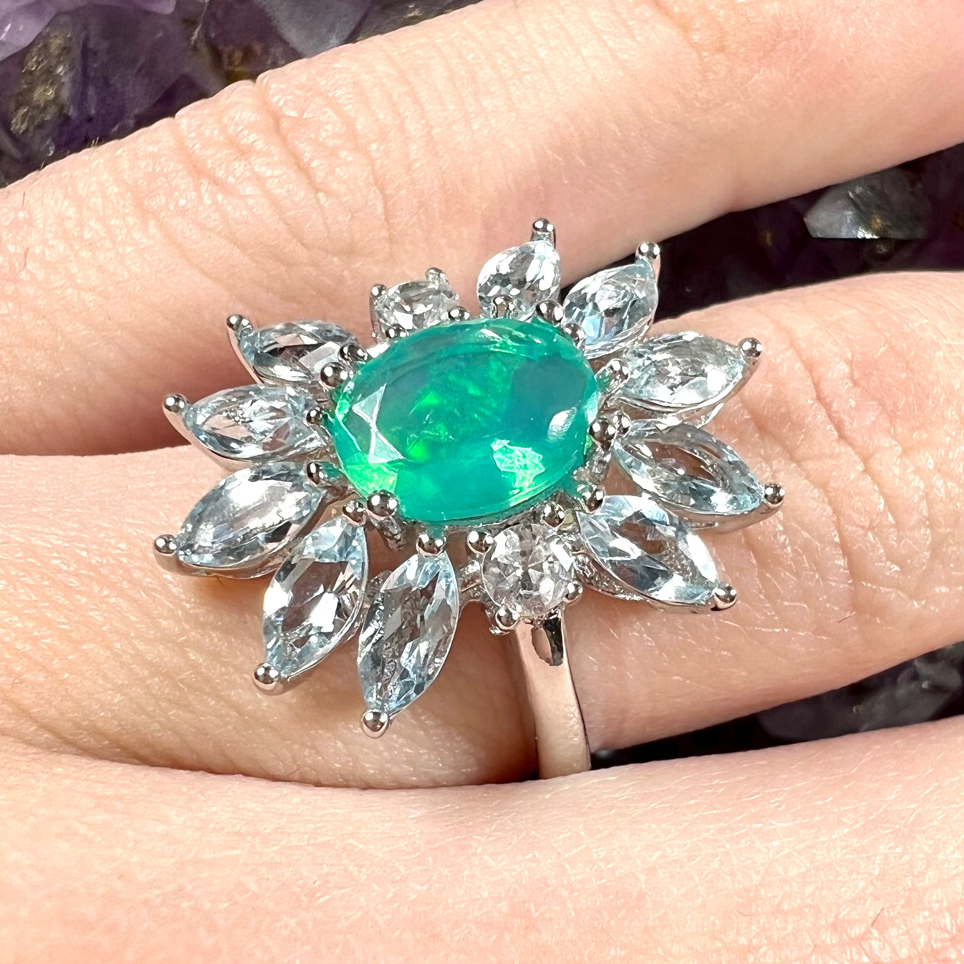 A faceted oval cut blue Ethiopian fire opal set in a sterling silver ring with marquise cut blue topaz stones.