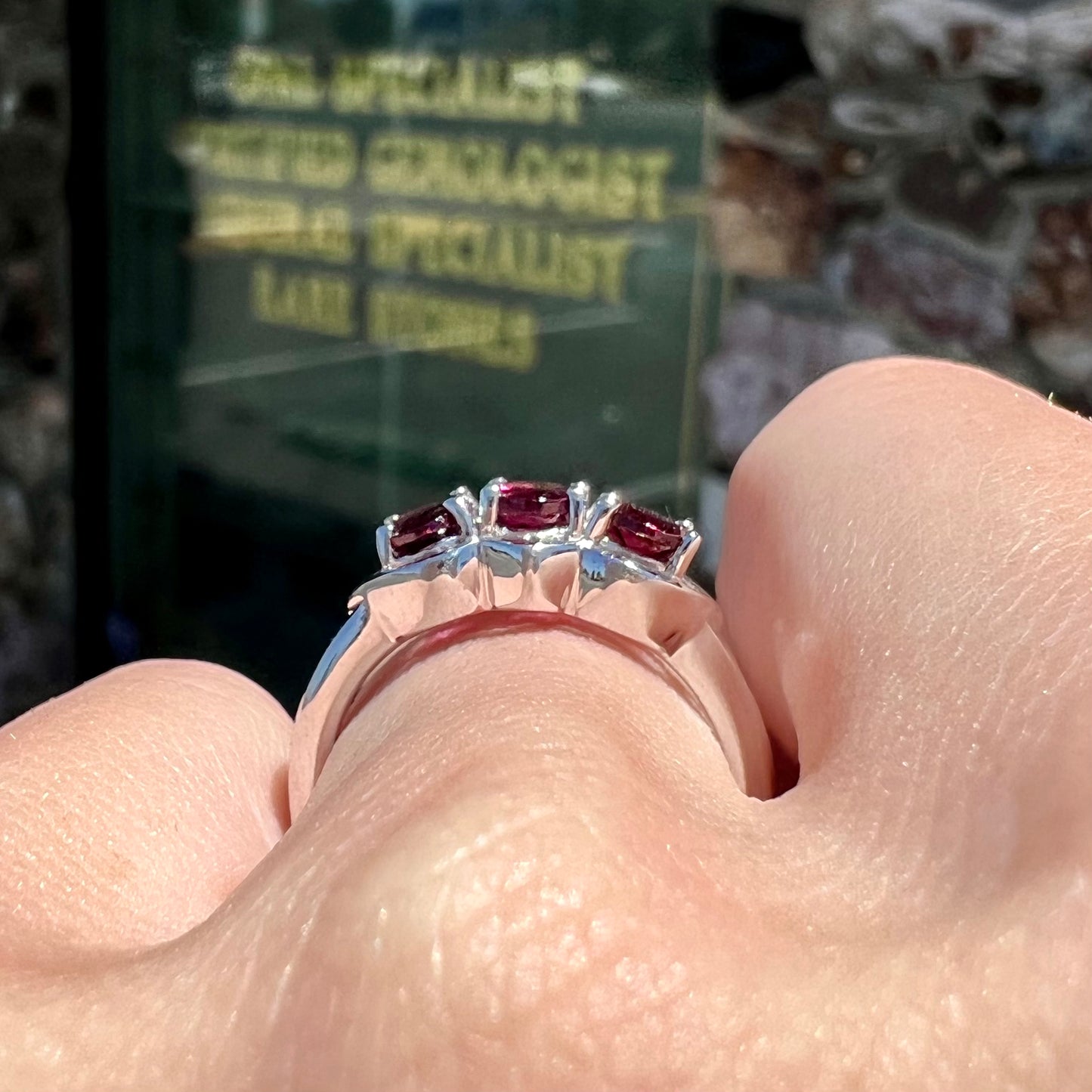 A three stone past, present, and future purple faceted oval cut rhodolite garnet ring.