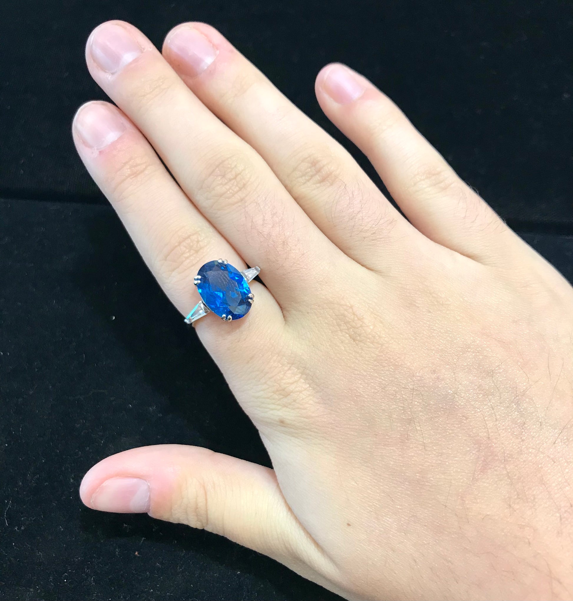 A sterling silver ring set with a faceted oval cut blue spinel and cubic zirconia baguettes.