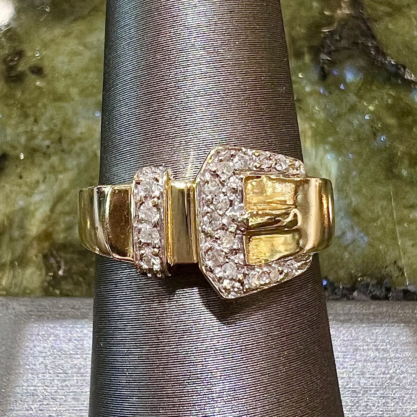 A yellow gold buckle ring set with round diamonds in the buckle.