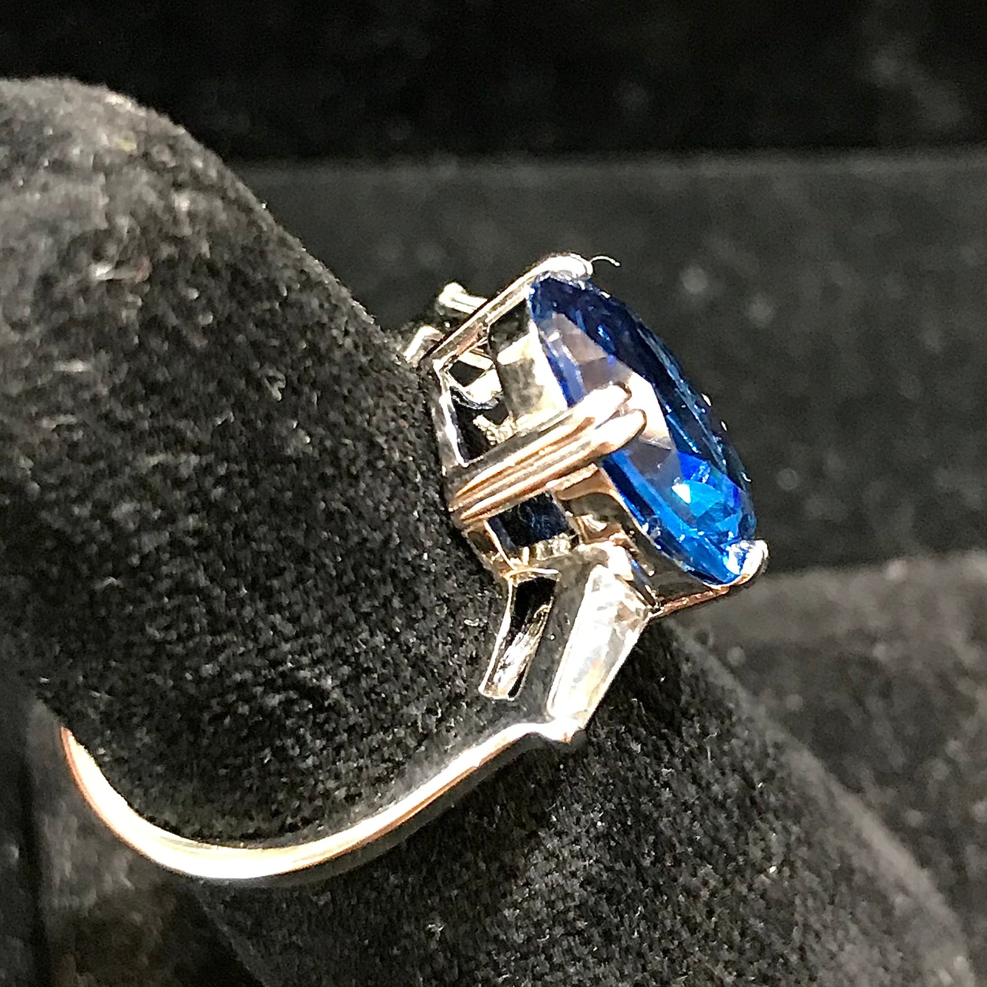 A sterling silver ring set with a faceted oval cut blue spinel and cubic zirconia baguettes.