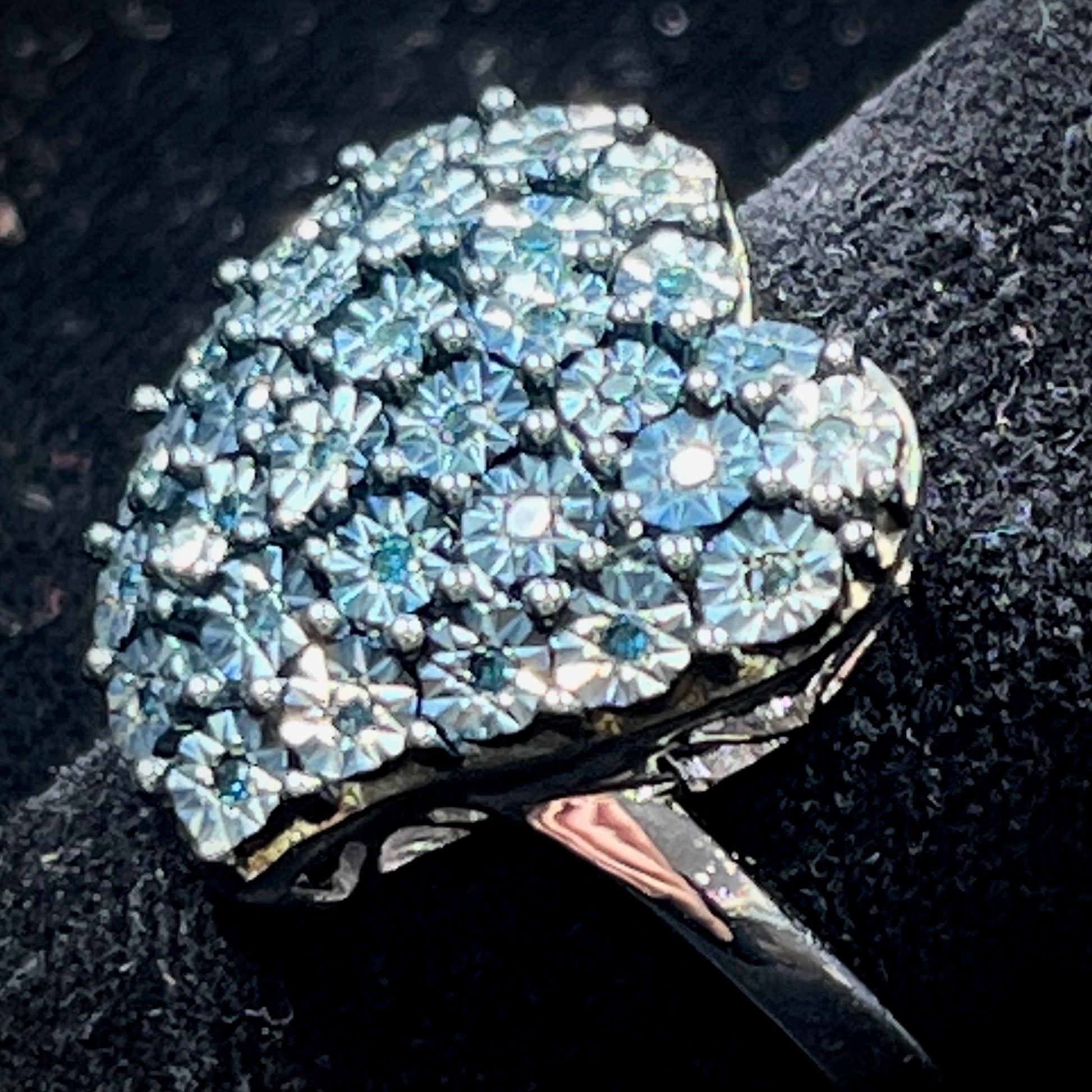 A sterling silver heart ring set with blue diamonds.