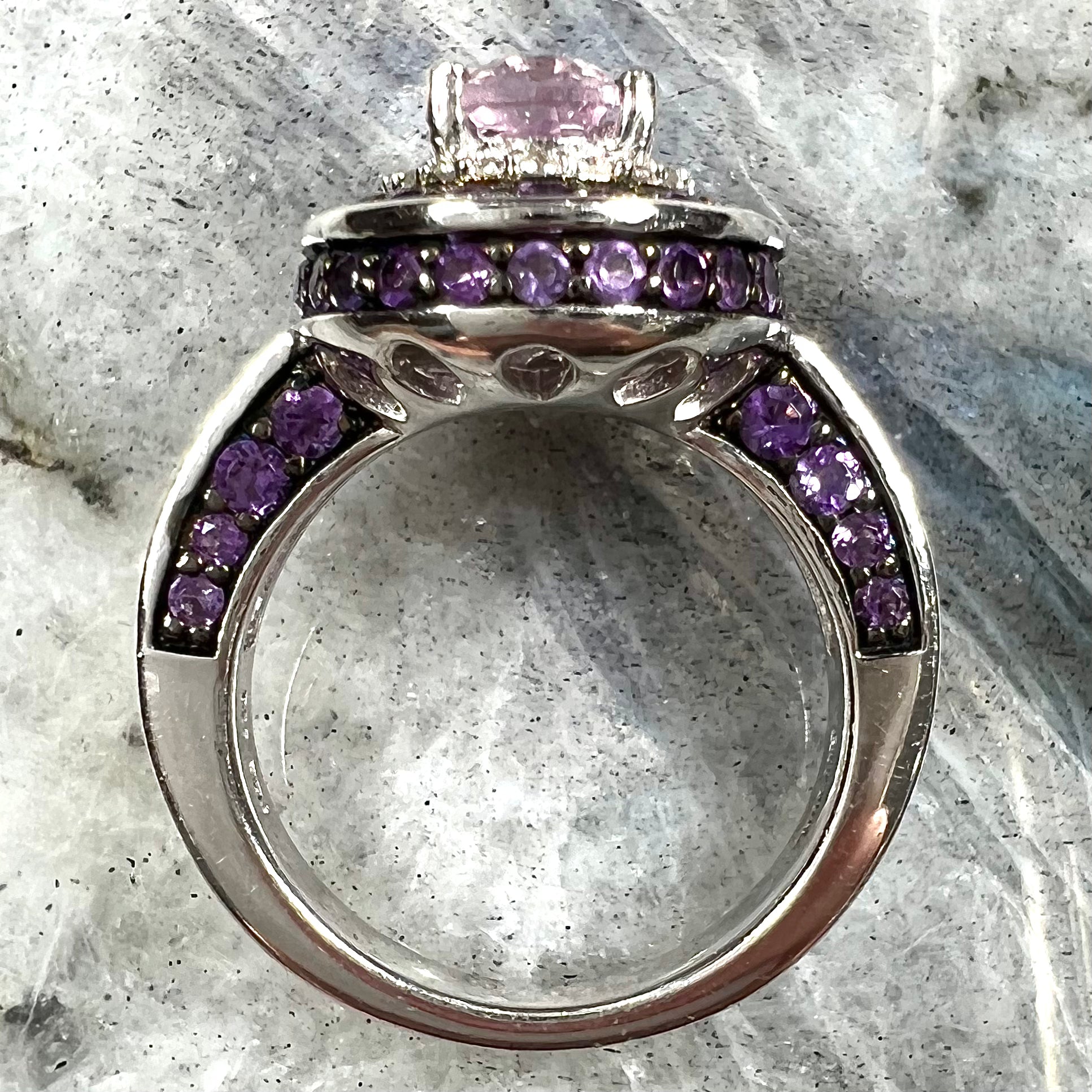 A sterling silver oval cut kunzite ring set with a double halo of round cut CZ and amethysts.