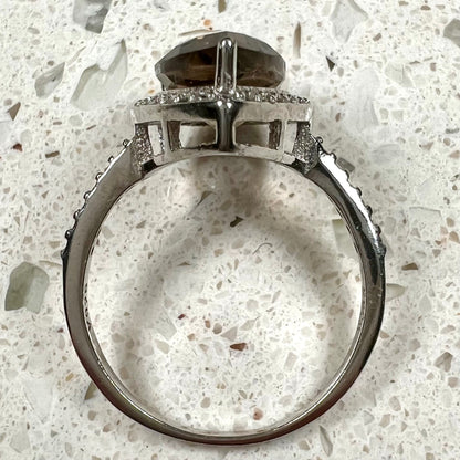 A pear shape smoky quartz set in a sterling silver and CZ halo ring.