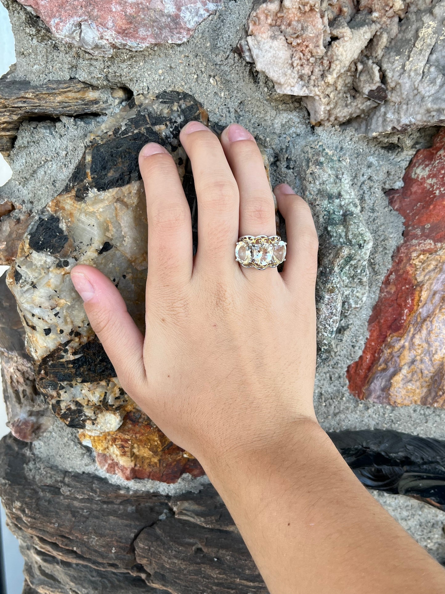 A sterling silver ring set with three oval cut golden beryl stones and yellow gold plated filigree accents.