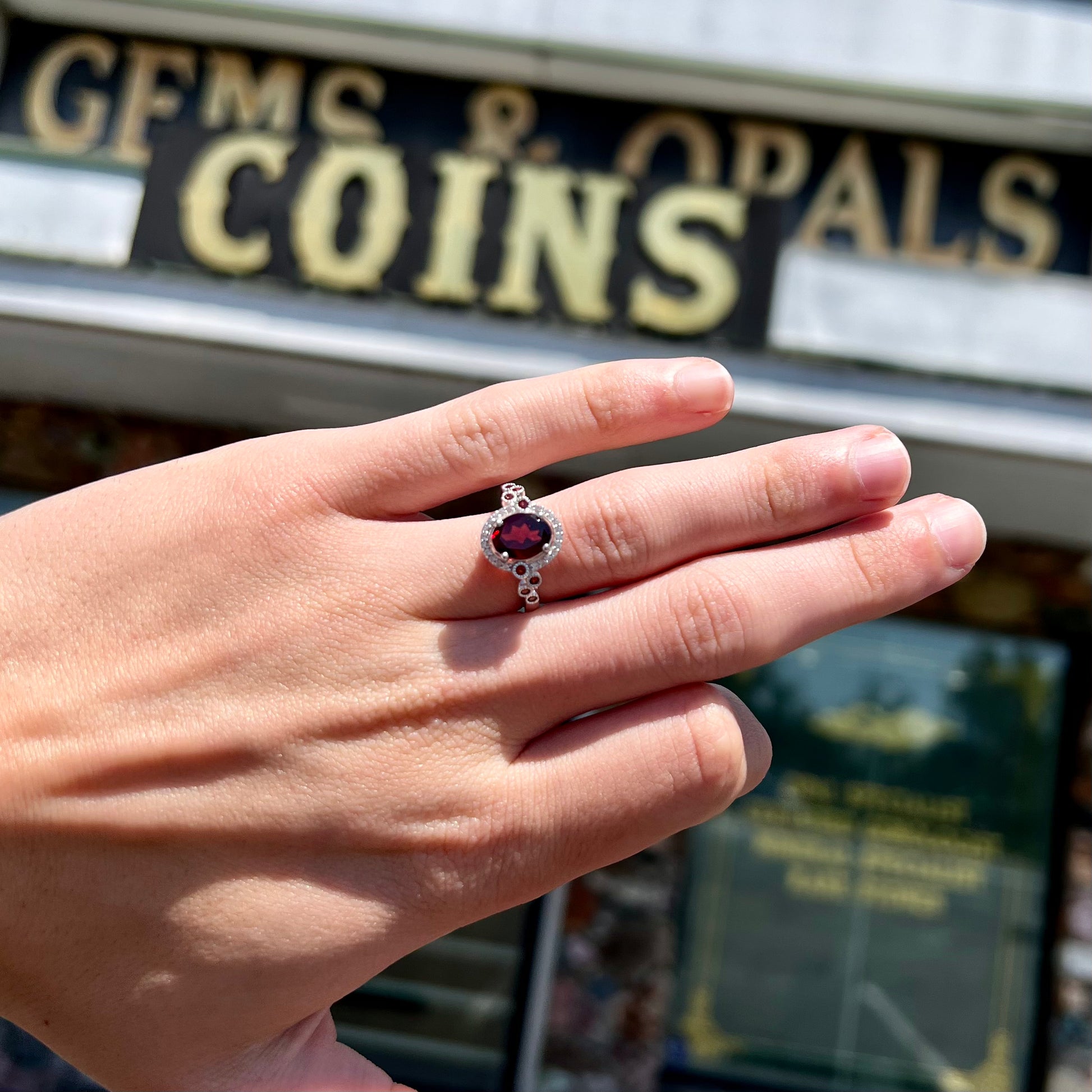 A silver garnet and CZ halo ring.  The center stone is a red almandine garnet, and the side garnets are orange.