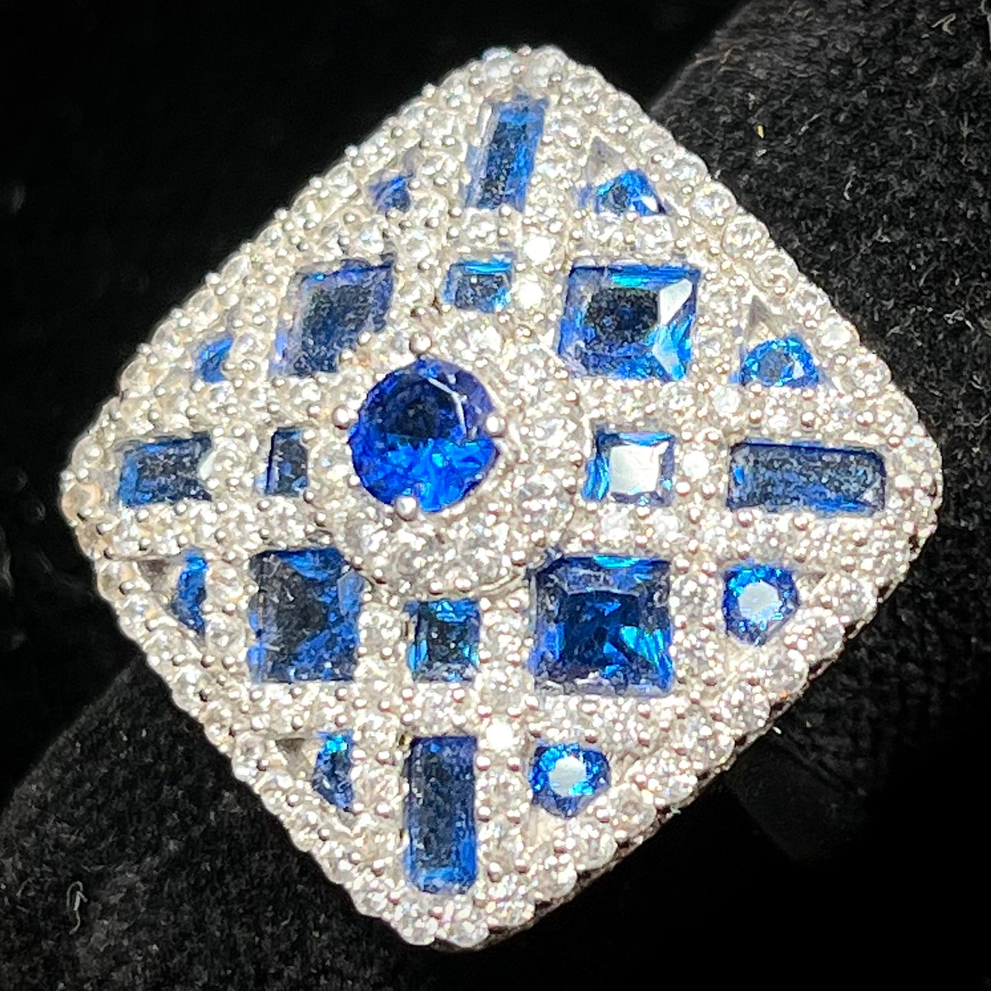 A sterling silver blue and white synthetic stone ring.  The ring strongly resembles a blueberry pie.