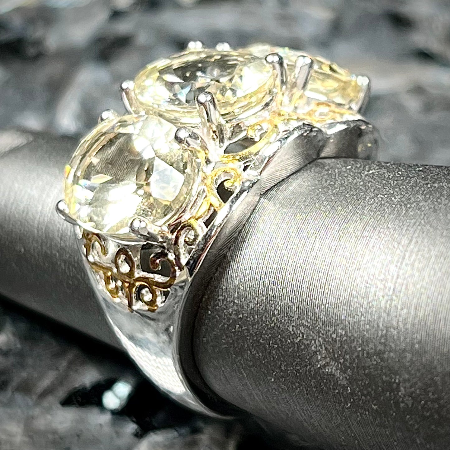 A sterling silver ring set with three oval cut golden beryl stones and yellow gold plated filigree accents.