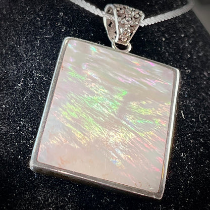 A sterling silver pendant set with rectangular slices of abalone shell and red fossil coral.