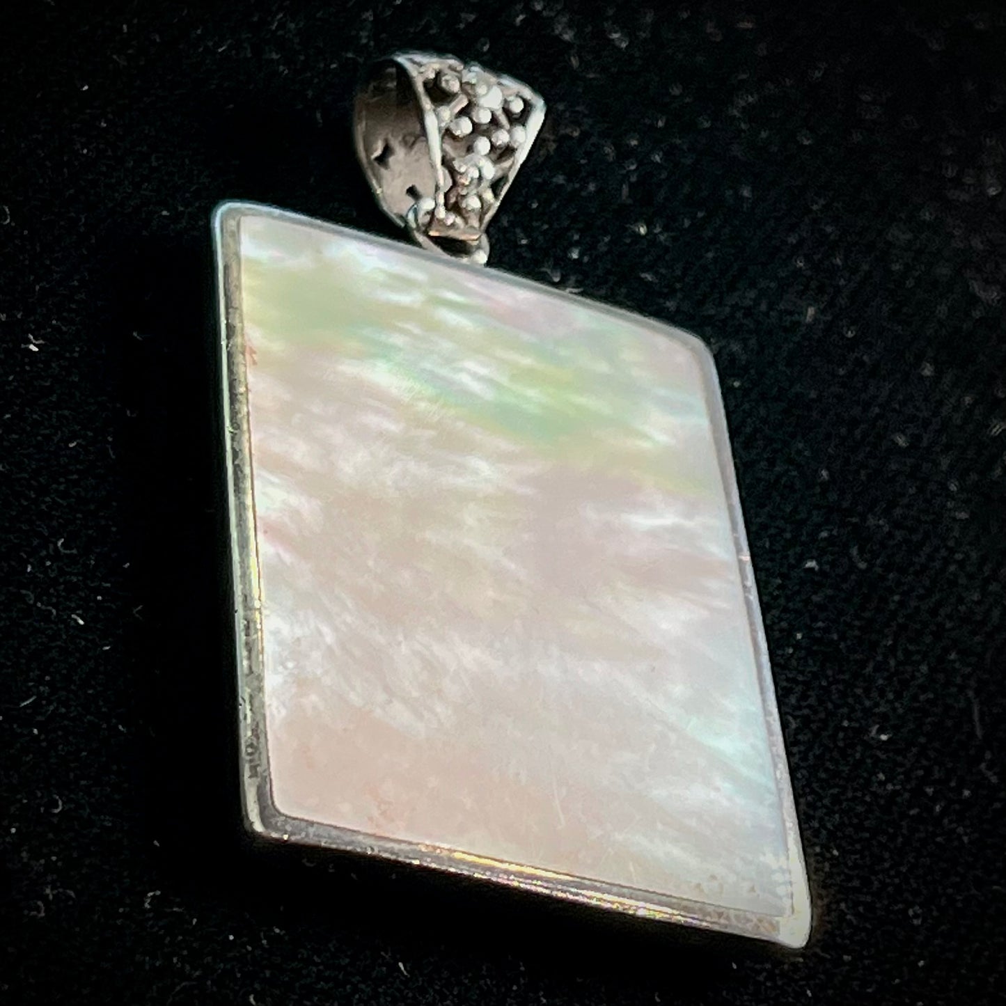 A sterling silver pendant set with rectangular slices of abalone shell and red fossil coral.