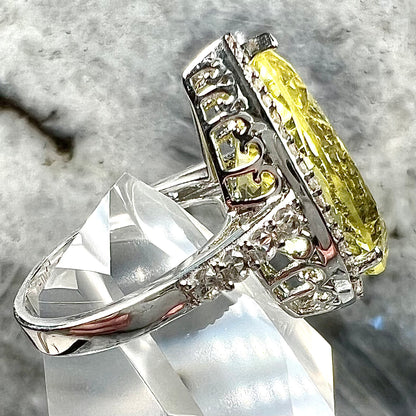 A pear shape lemon quartz set in a sterling silver and white topaz halo ring.