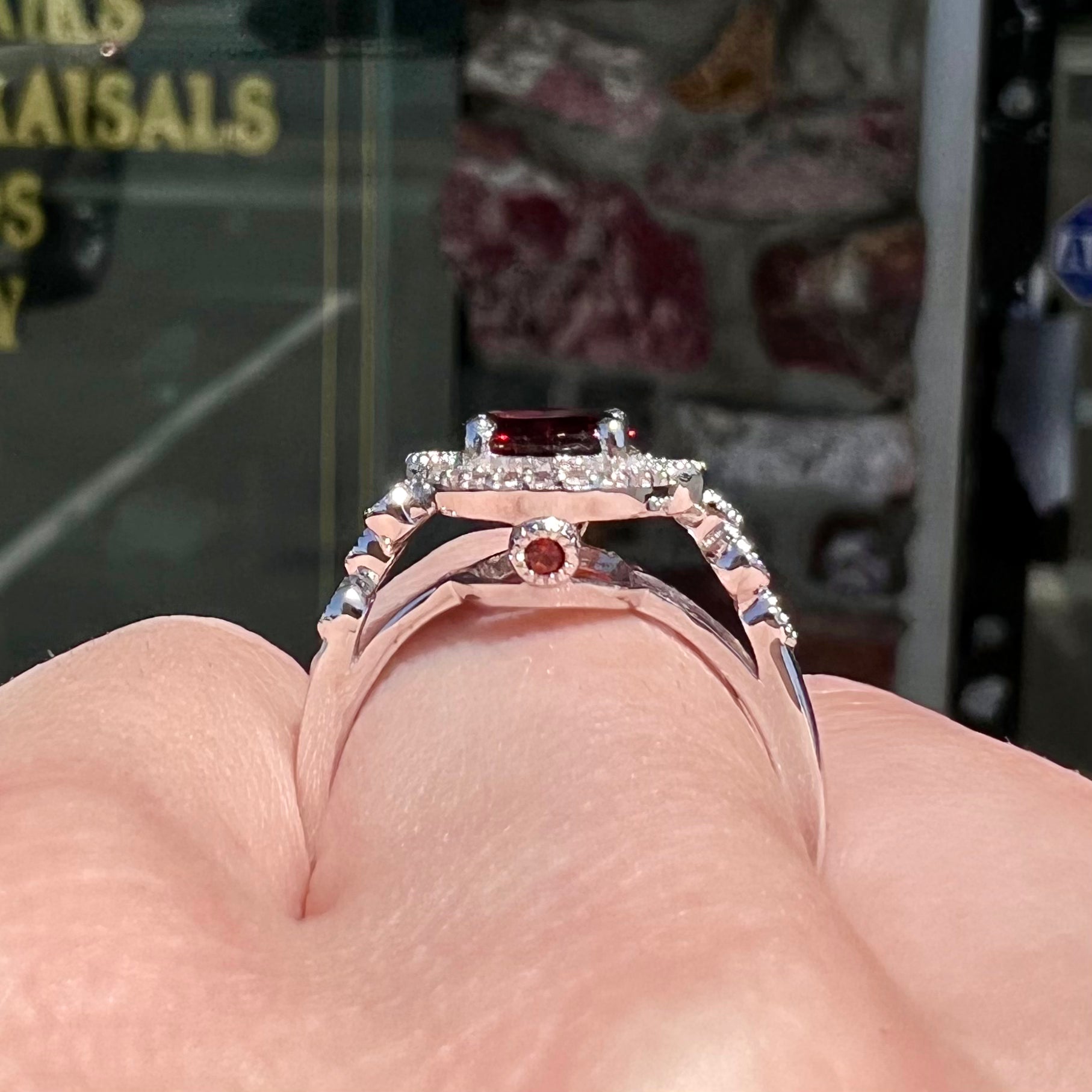 A silver garnet and CZ halo ring.  The center stone is a red almandine garnet, and the side garnets are orange.