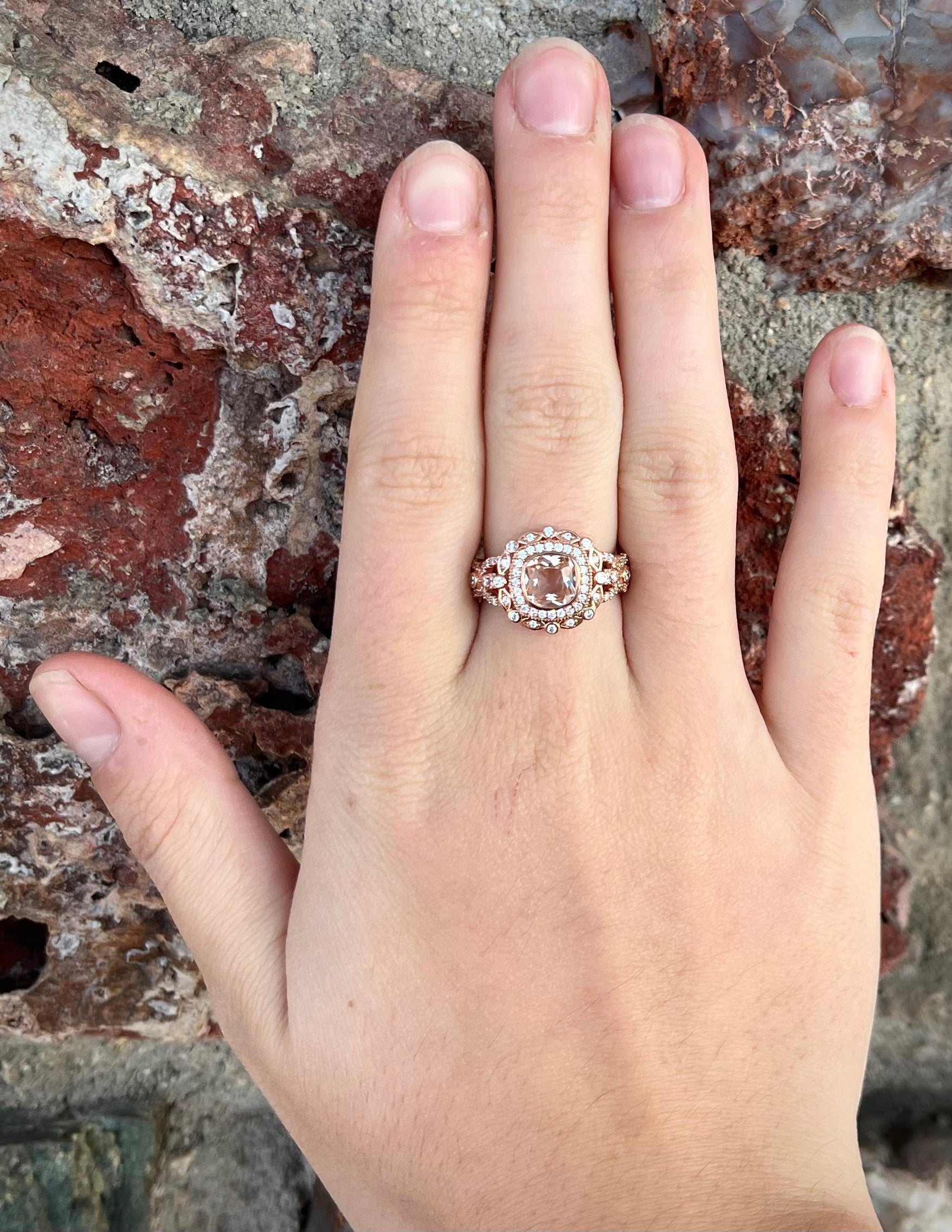 A rose gold plated ring set with a cushion cut morganite stone surrounded by cubic zirconia halos.