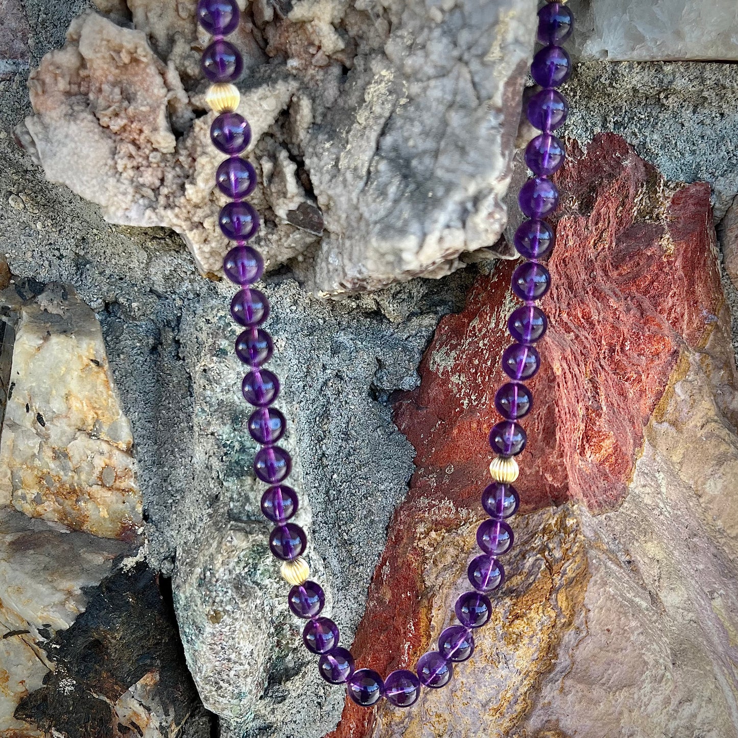 A beaded necklace made with round amethyst and 14k yellow gold beads.