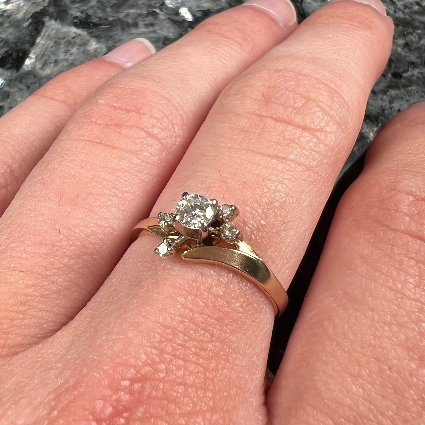 A yellow gold high-set diamond ring with four side diamonds.