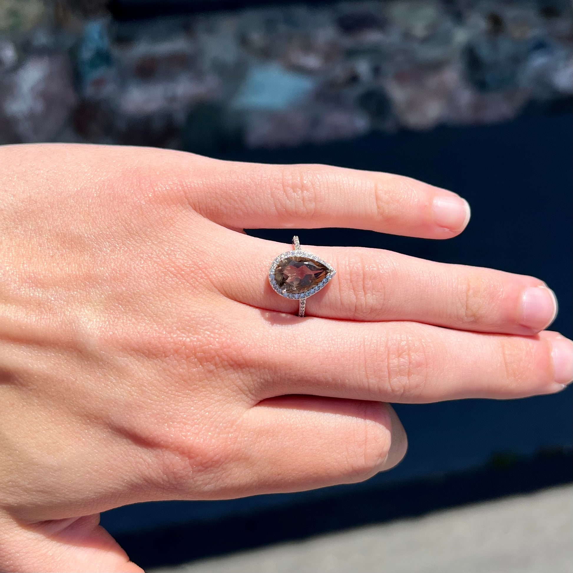A pear shape smoky quartz set in a sterling silver and CZ halo ring.