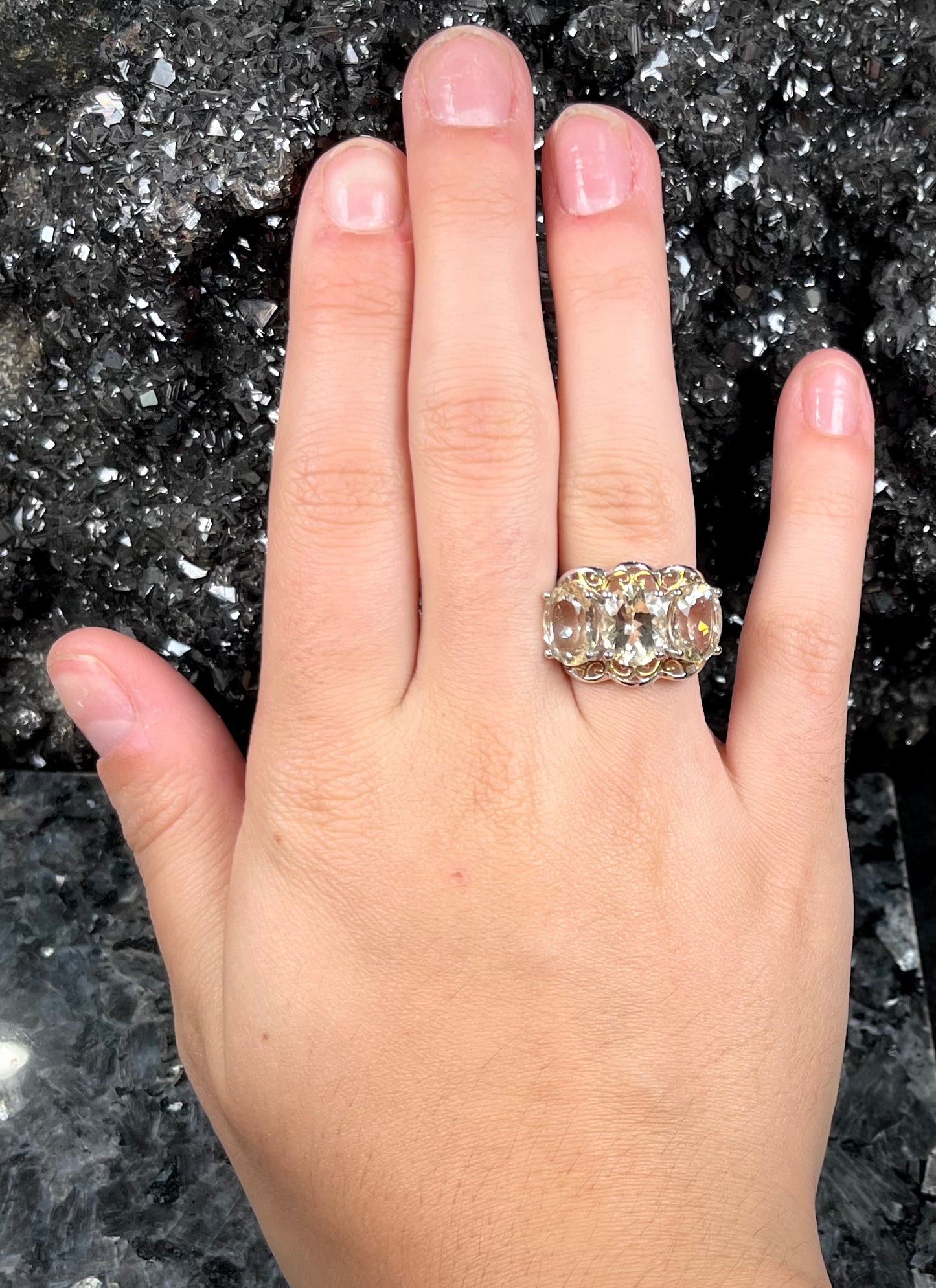 A sterling silver ring set with three oval cut golden beryl stones and yellow gold plated filigree accents.