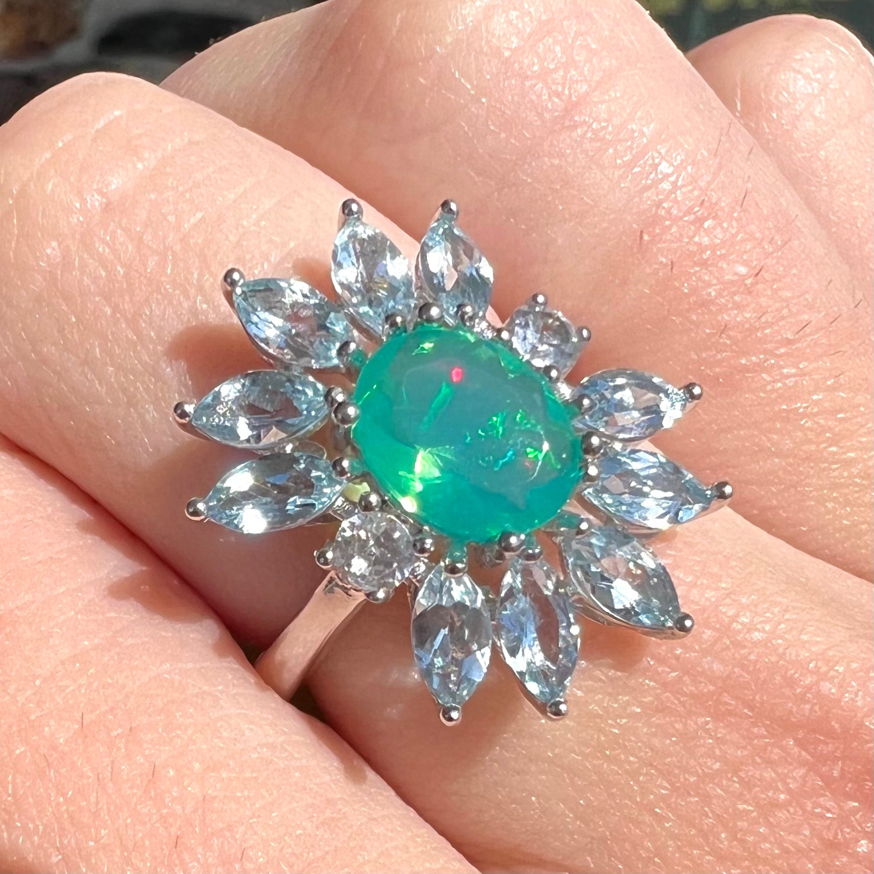 A faceted oval cut blue Ethiopian fire opal set in a sterling silver ring with marquise cut blue topaz stones.