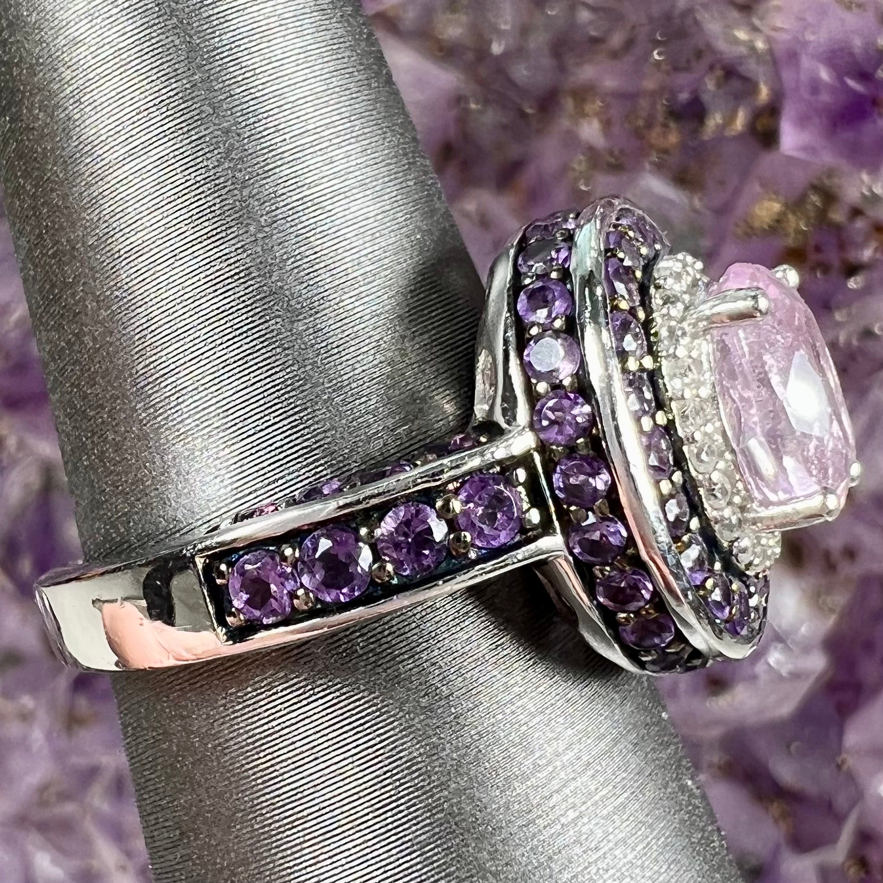 A sterling silver oval cut kunzite ring set with a double halo of round cut CZ and amethysts.