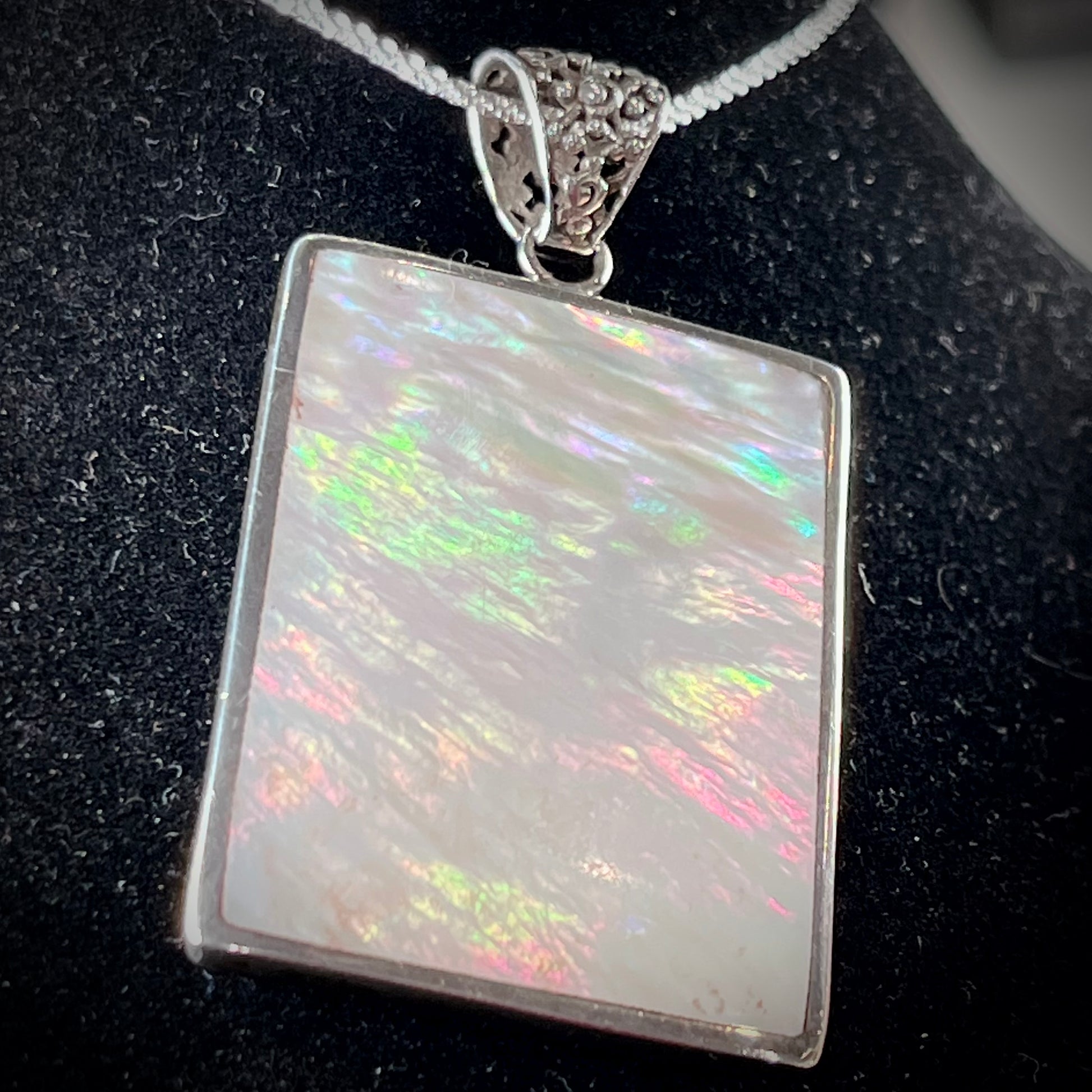 A sterling silver pendant set with rectangular slices of abalone shell and red fossil coral.