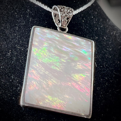 A sterling silver pendant set with rectangular slices of abalone shell and red fossil coral.