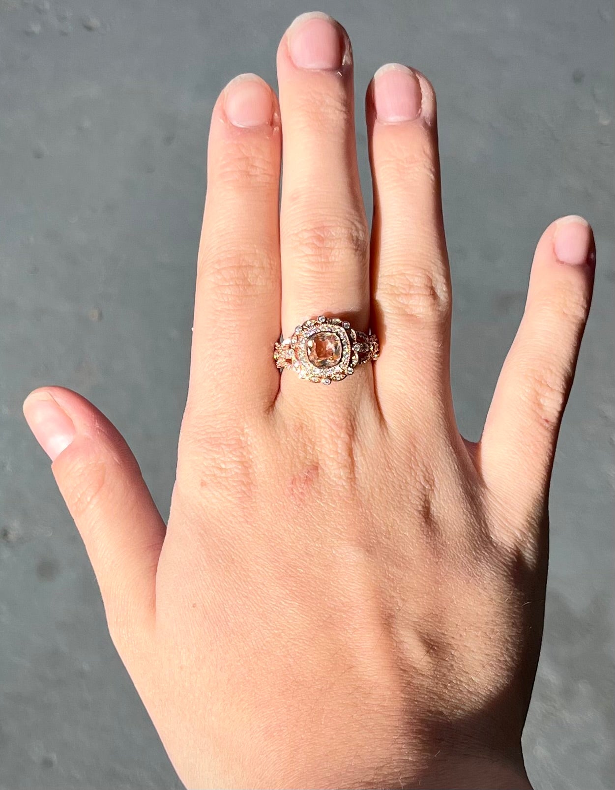 A rose gold plated ring set with a cushion cut morganite stone surrounded by cubic zirconia halos.