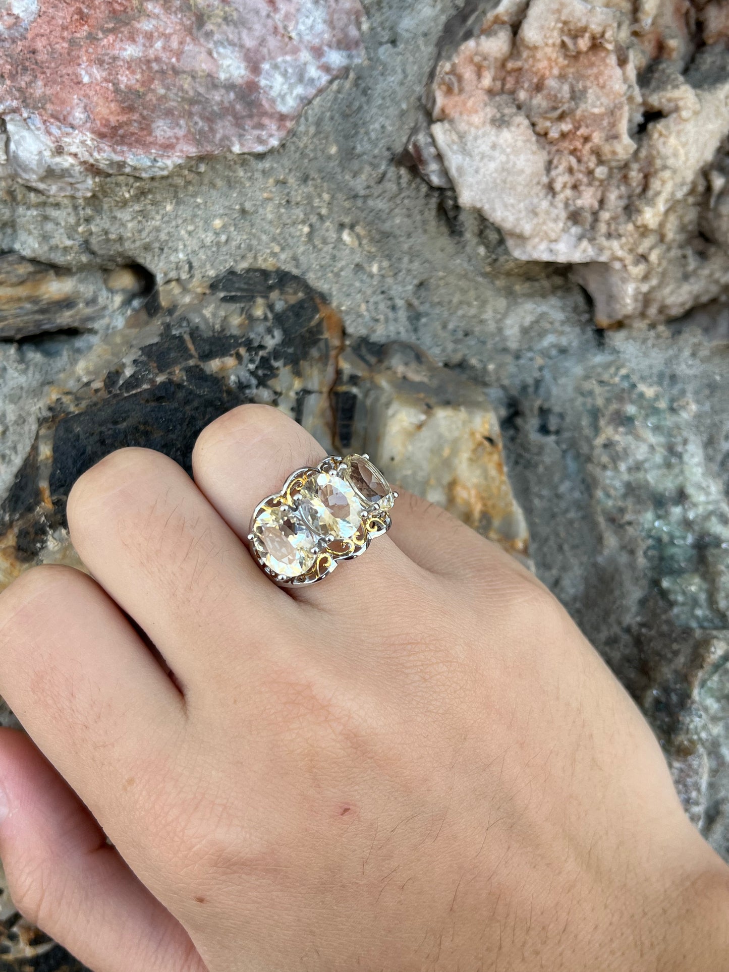 A sterling silver ring set with three oval cut golden beryl stones and yellow gold plated filigree accents.