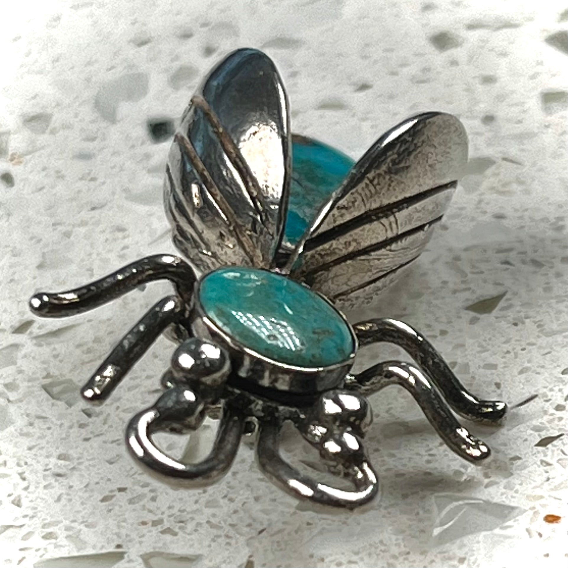 A sterling silver brooch made in the shape of a bee set with two turquoise stones for the head and body.