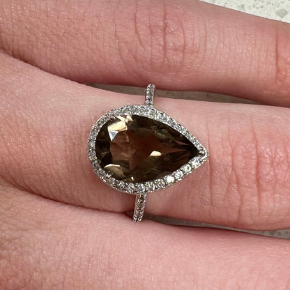 A pear shape smoky quartz set in a sterling silver and CZ halo ring.