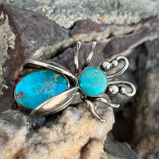 A sterling silver brooch made in the shape of a bee set with two turquoise stones for the head and body.