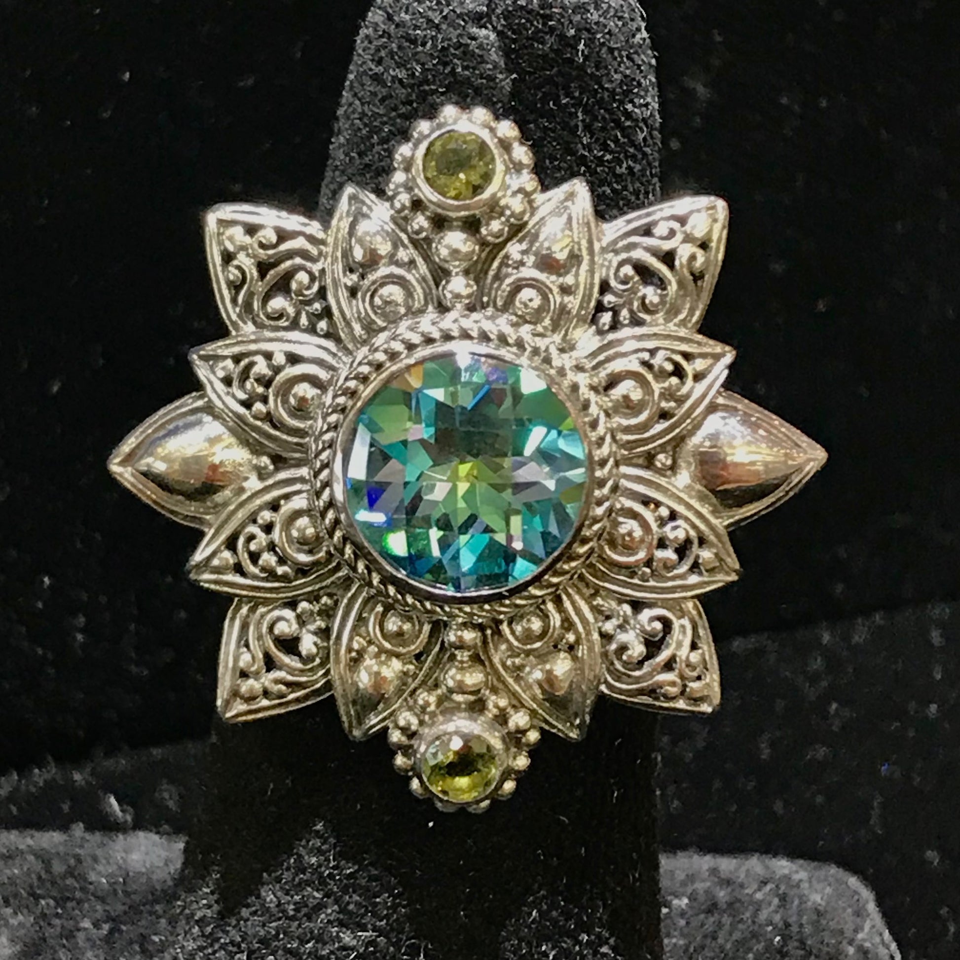 Sterling silver filigree flower design bezel set with synthetic multicolored gemstones.
