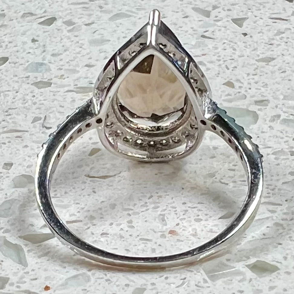 A pear shape smoky quartz set in a sterling silver and CZ halo ring.