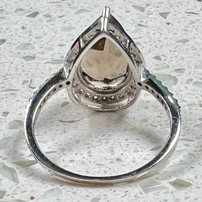 A pear shape smoky quartz set in a sterling silver and CZ halo ring.