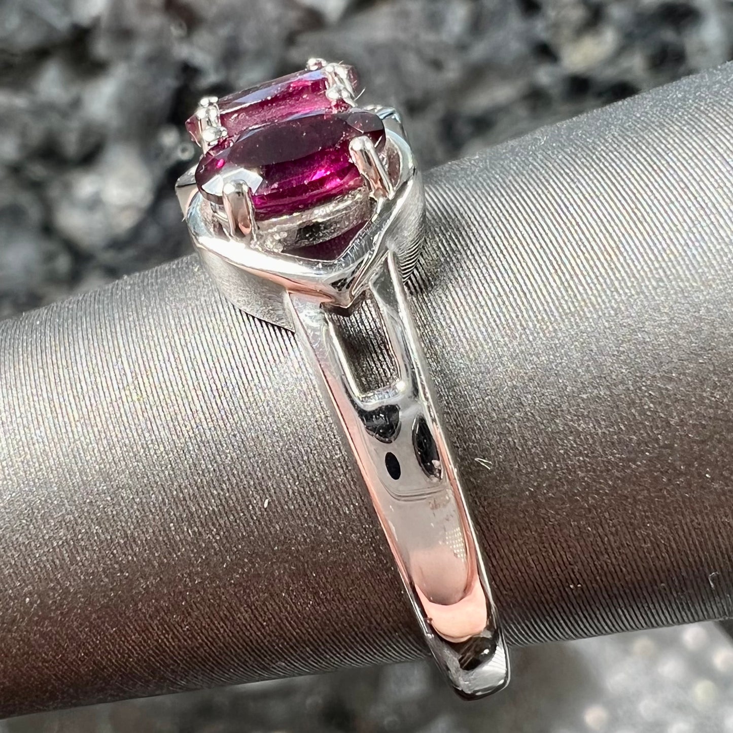 A three stone past, present, and future purple faceted oval cut rhodolite garnet ring.