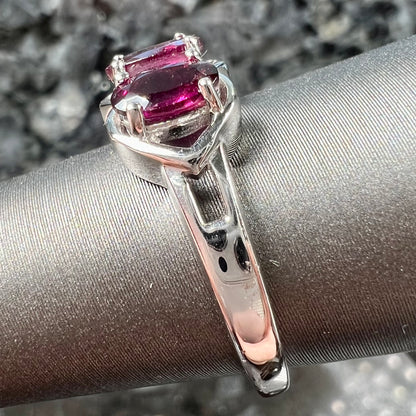A three stone past, present, and future purple faceted oval cut rhodolite garnet ring.