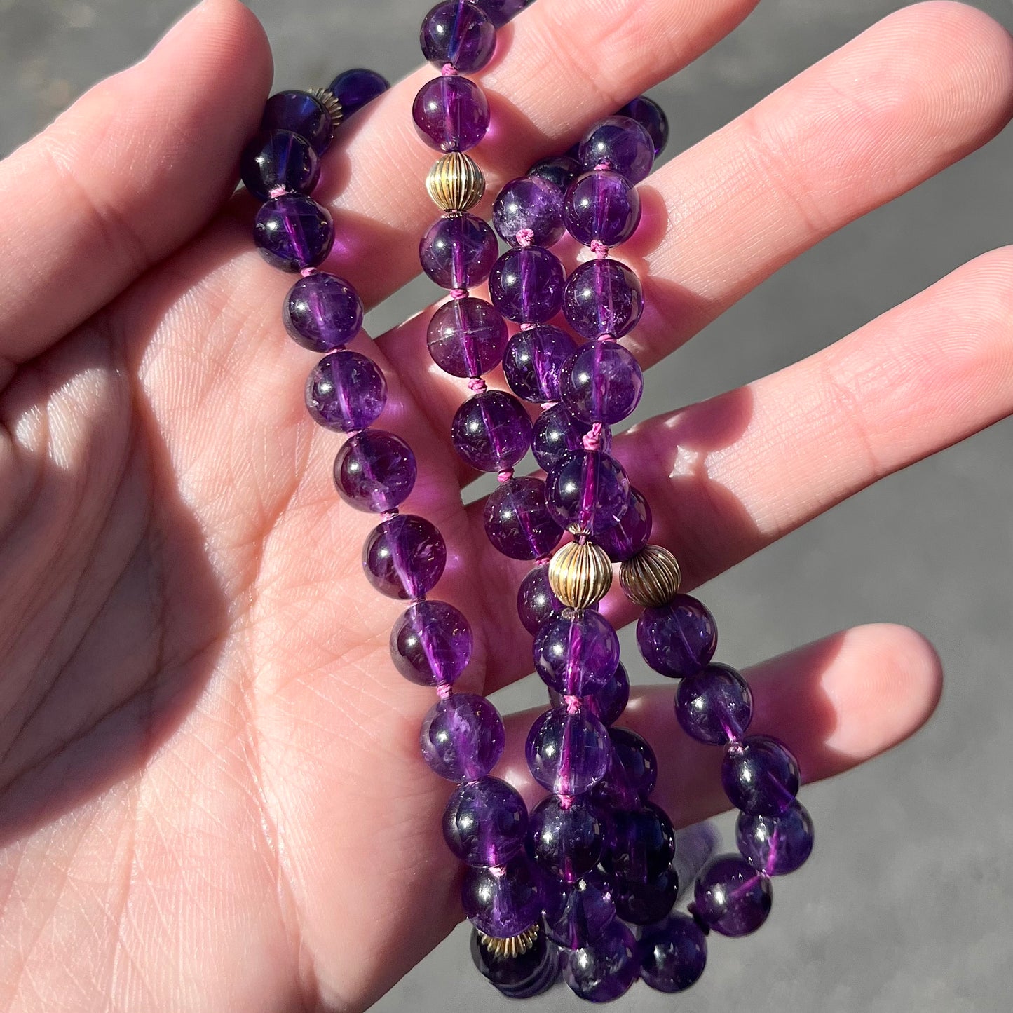 A beaded necklace made with round amethyst and 14k yellow gold beads.