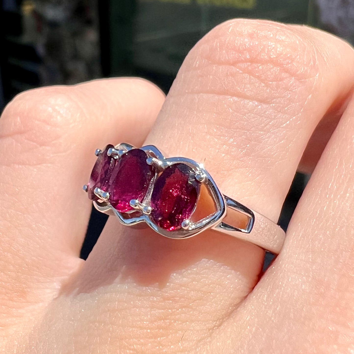 A three stone past, present, and future purple faceted oval cut rhodolite garnet ring.