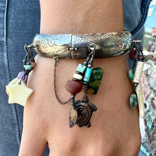 A Native American sterling silver bangle bracelets attached with carved bone, gemstone, and silver charm fetishes.