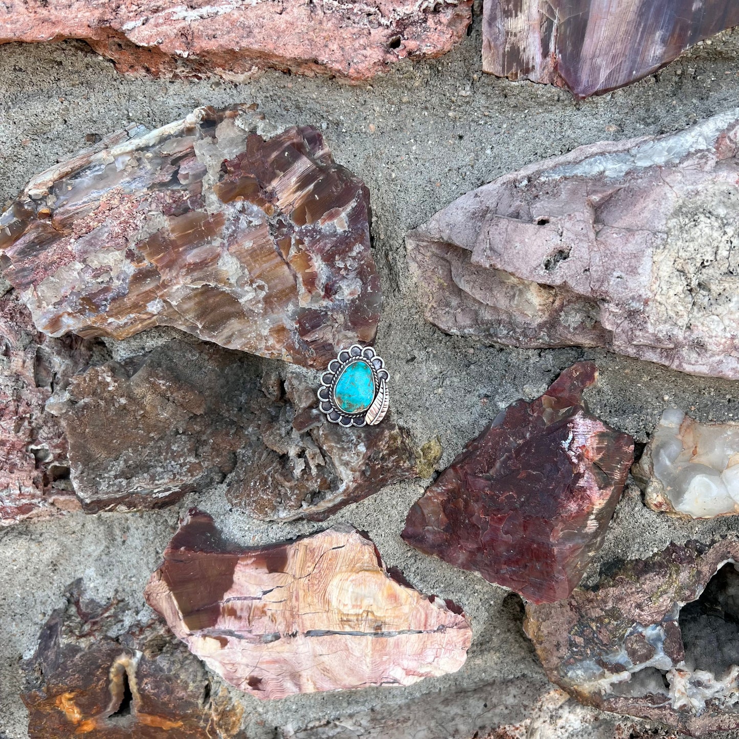 A sterling silver Navajo style ring.  The ring is set with a turquoise stone from Pilot Mountain.  There is a feather decoration next to the stone.